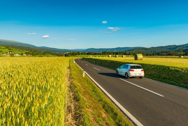 Un coche blanco conduce entre campos pintorescos en algún lugar de Austria