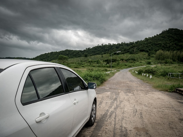 El coche blanco se dirige a la ruta natural y las nubes de tormenta están llegando.