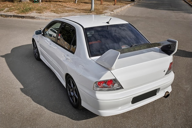 Foto coche blanco en un fondo de calle coche deportivo moderno de la ciudad con un papel pintado de spoiler