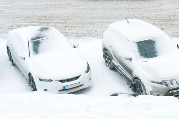 Foto coche blanco bajo la nieve en fuerte ventisca