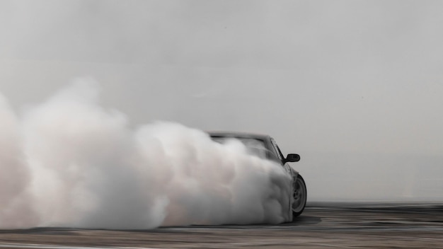 Foto coche borroso a la deriva de difusión de carreras a la deriva con mucho humo de neumáticos en llamas en la pista de velocidad