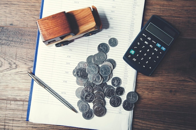 Coche con calculadora y dinero en mesa de madera