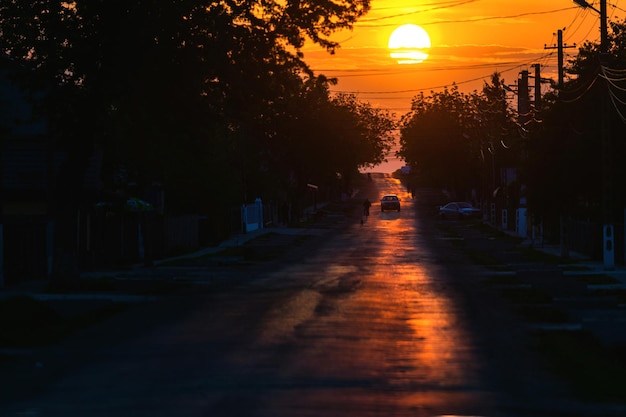 Coche en la calle contra el cielo naranja durante la puesta de sol