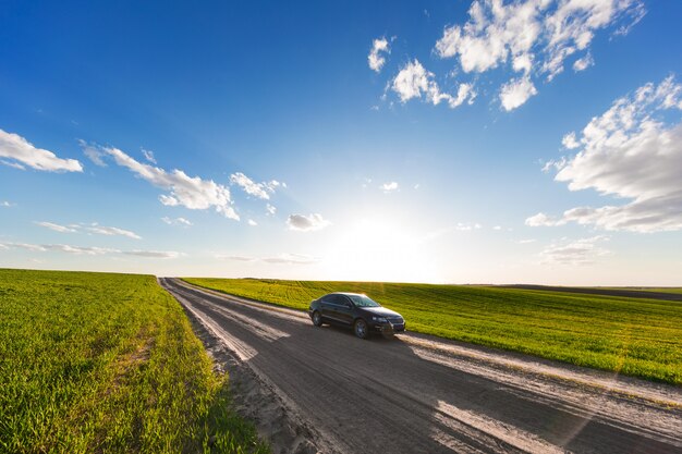 Foto coche en un camino de tierra y un campo con hierba verde