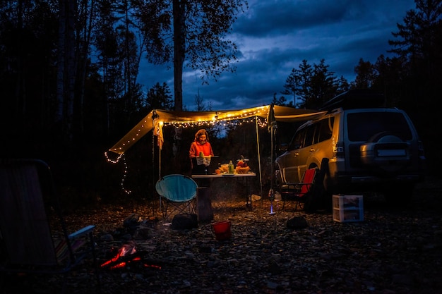 Coche de camping en el bosque de otoño cerca del río por la noche