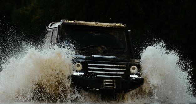 El coche de carreras de arrastre quema caucho Extreme Mudding está recorriendo un área de lodo húmedo o arcilla.