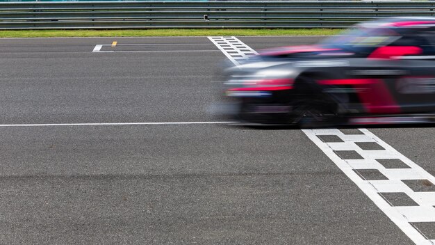 Foto coche de carreras con movimiento borroso cruzando la línea de meta en el circuito internacional de velocidad