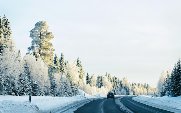 Coche en carretera de invierno con nieve en Finlandia. Auto y paisaje frío de Laponia. Automóvil en el bosque de Europa. Paseo por la autopista de la ciudad finlandesa. Carretera y ruta callejera nevada. Conduciendo