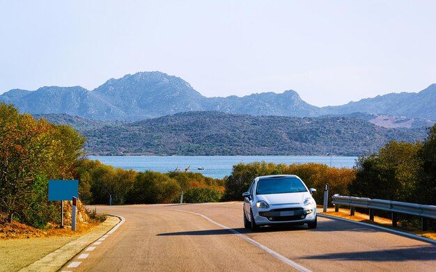 Coche en la carretera en Porto Cervo en Costa Smeralda en la isla de Cerdeña en verano de Italia. Transporte conduciendo por la autopista de Europa. Ver en la autopista. provincia de Olbia. Técnica mixta.