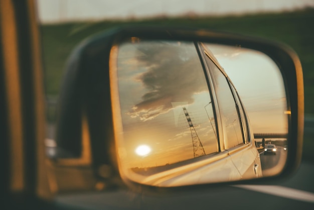 Coche en carretera puesta de sol en reflejo de espejo de coche