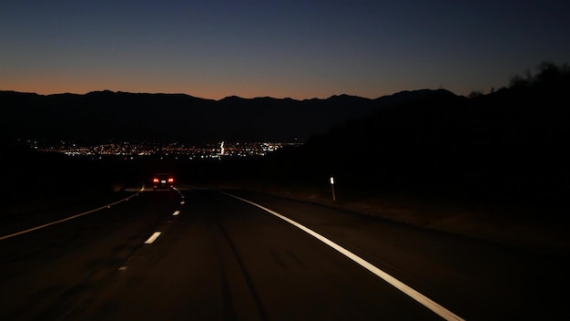 Foto coche en la carretera del valle del desierto en la carretera de noche en el crepúsculo viaje por carretera en ee. uu.