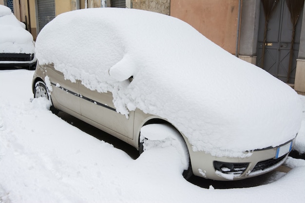 Coche cubierto y rodeado de nieve después de una tormenta de nieve