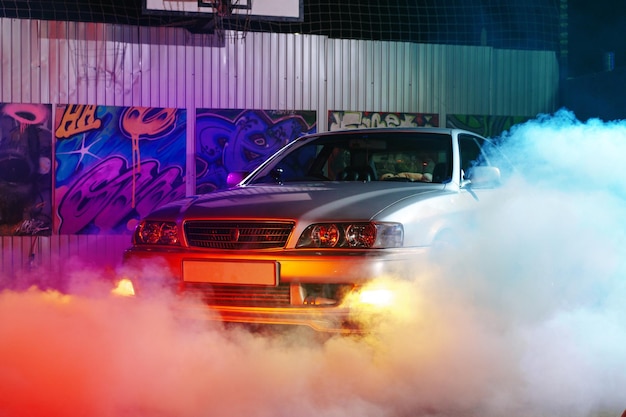 Coche deportivo en la calle de la ciudad nocturna a la luz de neón con humo