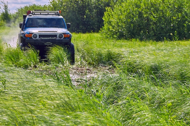 Coche deportivo con tracción en las cuatro ruedas corre a través de la hierba verde