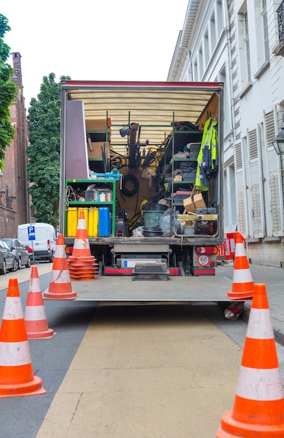 Coche con equipo de construcción en la calle en la vieja ciudad europea. Ingeniería urbana, Europa, sitio de construcción en la carretera