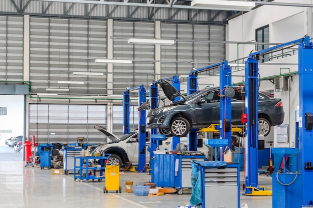 Foto coche en el equipo de elevación en el garaje siendo reparado y reparado.