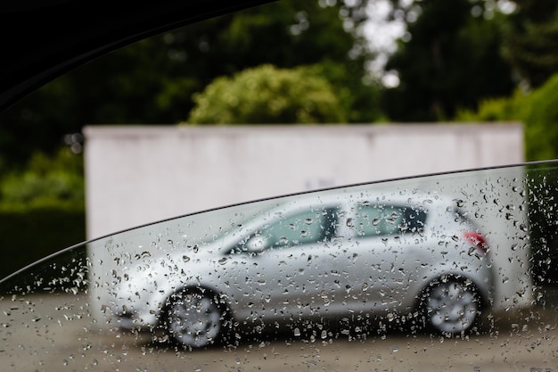 Coche estacionado en la calle visto a través de una ventana húmeda