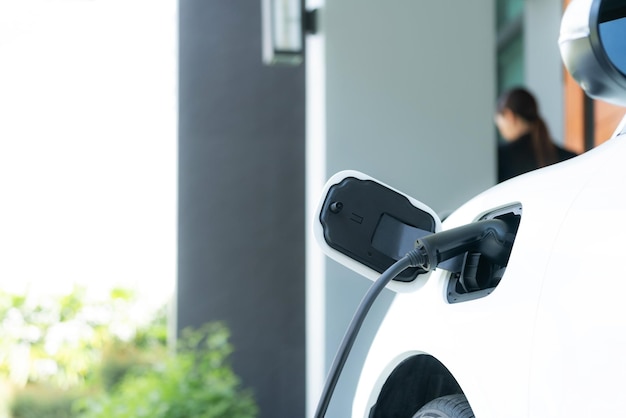 Coche Focus EV en la estación de carga doméstica con una mujer progresiva borrosa en la parte de atrás