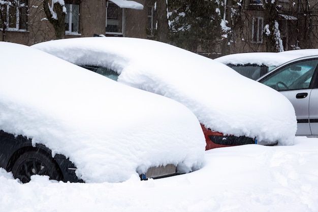 Coche bajo una gruesa capa de nieve después de la tormenta. Vehículos enterrados bajo hielo. Nadie