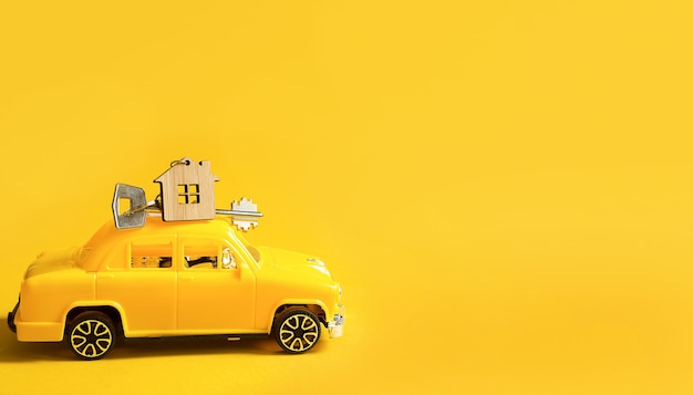 Coche de juguete amarillo con llave de la casa en el techo sobre un fondo de color. Mudarse a casa nueva, hipoteca, compra de apartamento, taxi. Copie el espacio.