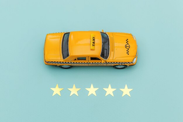 Coche de juguete amarillo Taxi Cab y 5 estrellas aisladas sobre fondo azul.