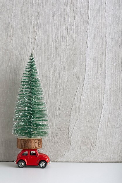 Coche de juguete con árbol de Navidad en el techo Coche como regalo debajo del árbol Marco vertical