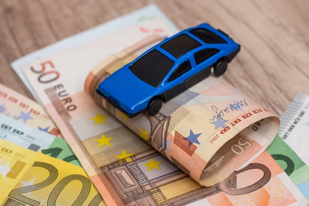Foto coche de juguete azul en billetes en euros