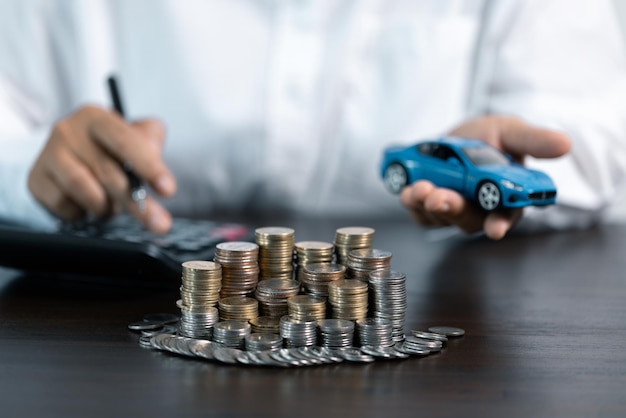 Coche de juguete azul frente al hombre de negocios calculando el préstamo ahorrando dinero para el concepto de coche comercio de automóviles por el concepto de efectivo concepto de financiación
