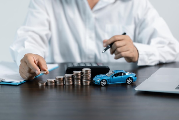 Coche de juguete azul frente al hombre de negocios calculando el préstamo ahorrando dinero para el concepto de coche comercio de automóviles por el concepto de efectivo concepto de financiación