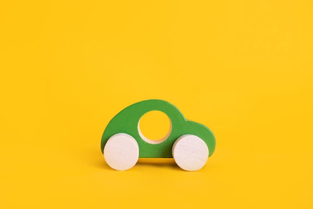 Foto coche de juguete de madera en estilo de dibujos animados sobre fondo amarillo colorido y fondo de transporte eco niño