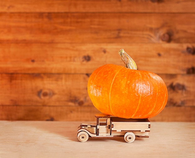 un coche de juguete de madera lleva una calabaza sobre una mesa de madera