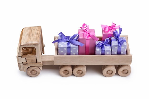 Coche de juguete de madera con regalos en cajas en la parte trasera.