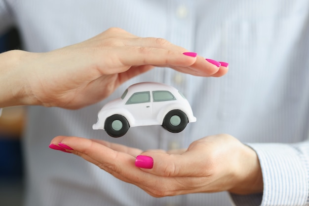 Foto coche de juguete en manos femeninas del agente de seguros