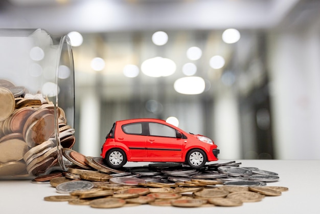 Coche de juguete y monedas de dinero en tarro de cristal.