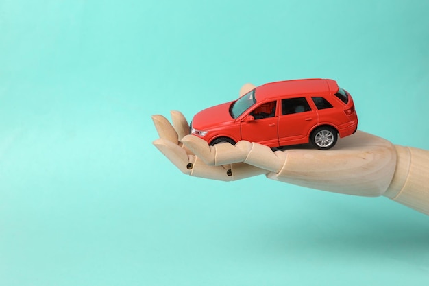 Coche de juguete en la palma de la mano de una mujer en fondo azul concepto de seguro de protección de automóviles