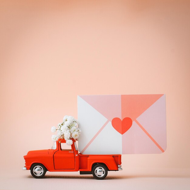 Coche de juguete retro pickup rojo que entrega correo y cartas de amor y flores