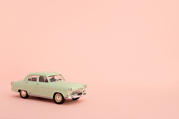 Coche de juguete retro verde sobre un fondo rosa