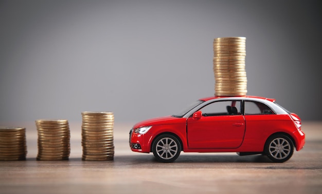 Coche de juguete rojo y monedas en el escritorio.