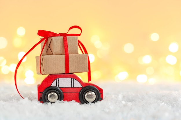 Coche de juguete rojo con pila de cajas de regalo de Navidad