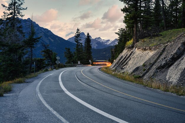 Coche ligero en la carretera con montañas rocosas en el parque nacional de Banff