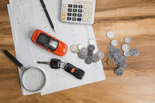 Coche con llave y monedas en documento.