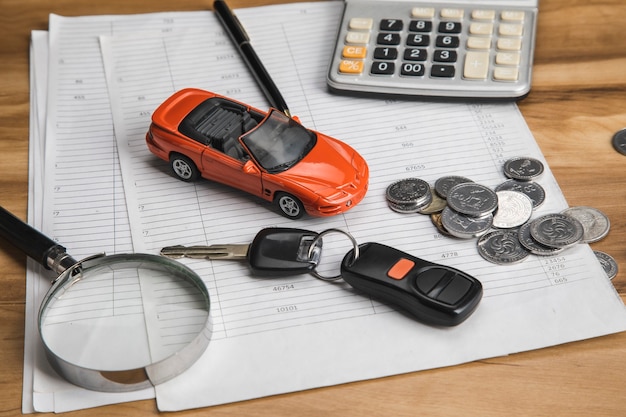 Coche con llave y monedas en documento.