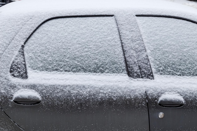 Foto coche negro cubierto de nieve en la vista lateral del primer plano de la luz del día nublado