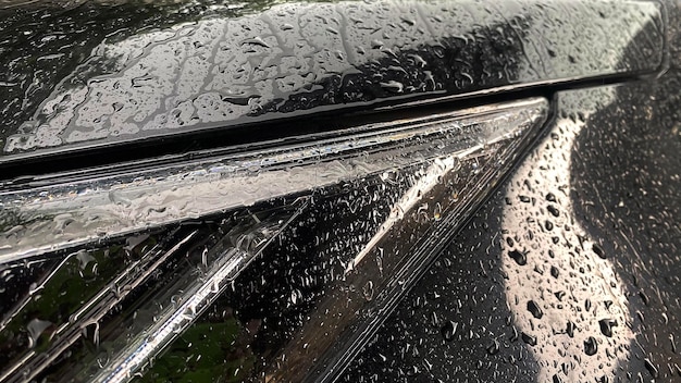 Un coche negro con un limpiaparabrisas y una gota de lluvia en el parabrisas.