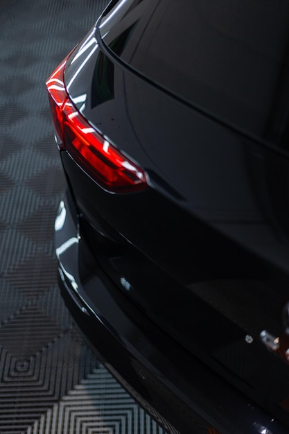 Coche negro con luz trasera en el garaje Lavado y detallado de automóviles Reparación