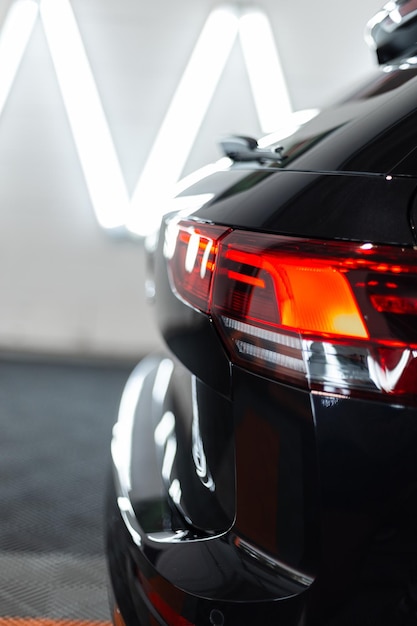Coche negro con luz trasera en el garaje Lavado y detallado de automóviles Reparación
