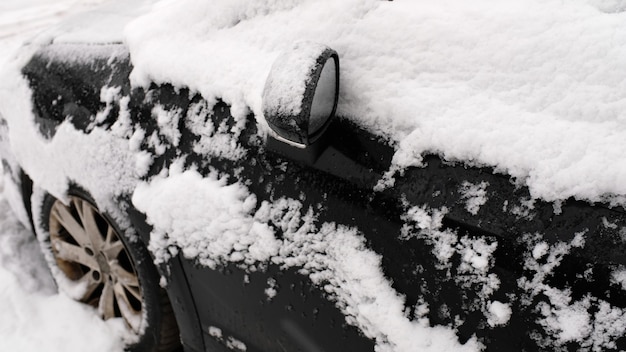 Coche negro en la nieve en el estacionamiento.