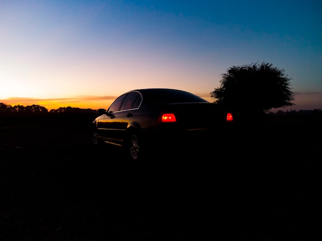 Coche negro sobre un fondo de cielo naranja