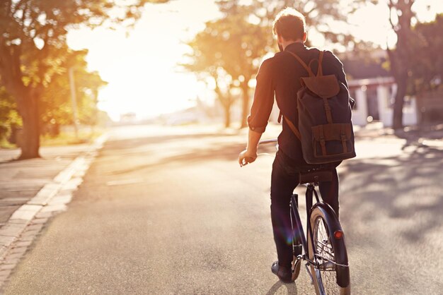 Sin coche, no hay problema Vista trasera de un joven montando en bicicleta al aire libre