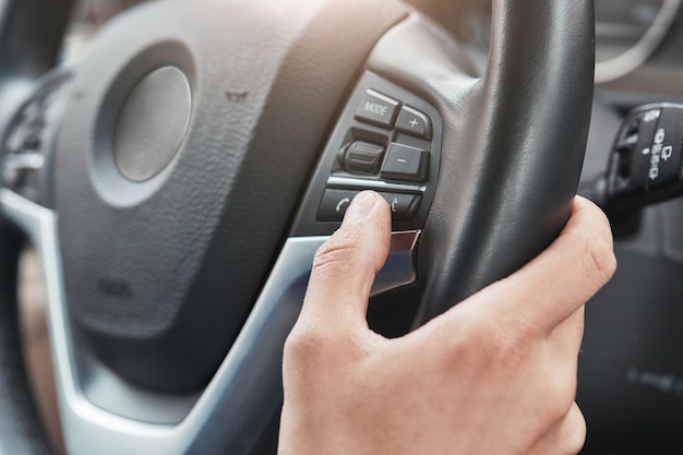 Coche nuevo imagen recortada de una mano presionando los botones de control en el volante en un